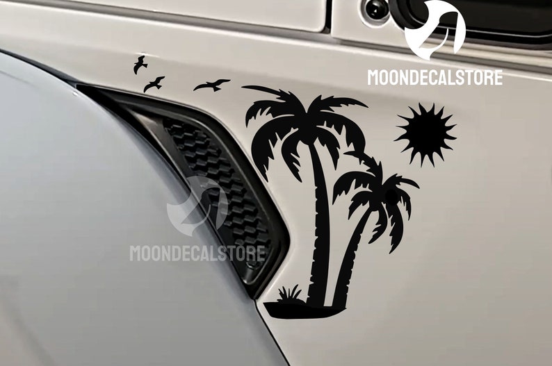 Puede incluir: Calcoman&iacute;a en blanco y negro de dos palmeras con un sol y algunas aves volando por encima. La calcoman&iacute;a est&aacute; en una puerta de coche blanca.