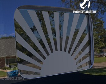 May include: A gray vinyl decal of a rising sun with rays emanating from the center. The decal is applied to the rear window of a vehicle. The decal is a popular design for car enthusiasts.