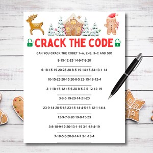 May include: A white paper with the text "CRACK THE CODE" and number sequences. Festive illustrations of a gingerbread house, a gingerbread man, and a reindeer decorate the paper. A black pen lies on the paper.