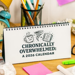 以下が含まれることがあります： 「Chronically Overwhelmed: A 2026 Calendar」の文字が入った卓上カレンダー。スパイラル綴じで、白い表紙には、悲しそうなコーヒーカップ、竜巻、ノートの黒いイラストが描かれています。 ターコイズ色の目覚まし時計とペンが背景にあります。