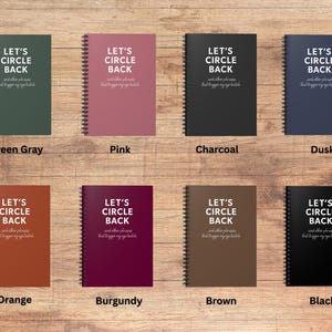 May include: A collection of spiral-bound notebooks in various colors, including green-gray, pink, charcoal, and dusk. Each notebook features the text "LET'S CIRCLE BACK" and a smaller line of text below. Additional colors are orange, burgundy, brown, and black.