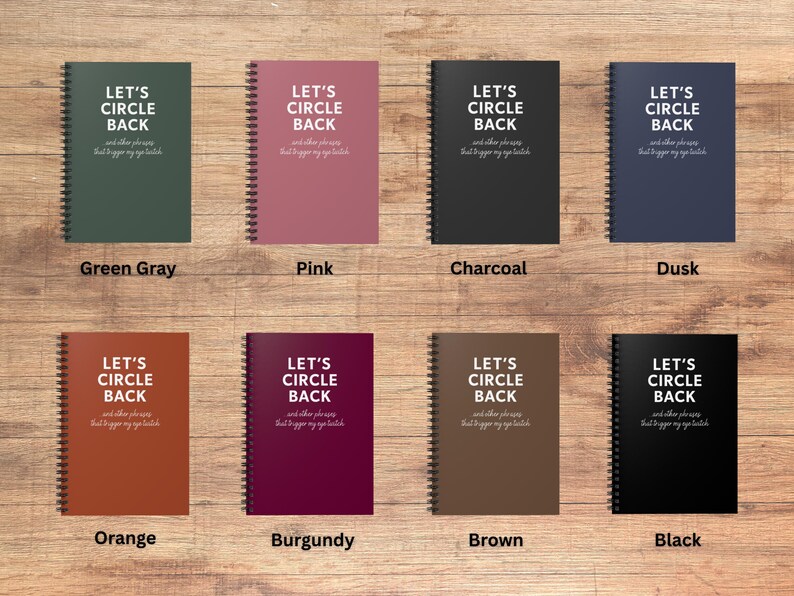May include: A collection of spiral-bound notebooks in various colors, including green-gray, pink, charcoal, and dusk. Each notebook features the text "LET'S CIRCLE BACK" and a smaller line of text below. Additional colors are orange, burgundy, brown, and black.