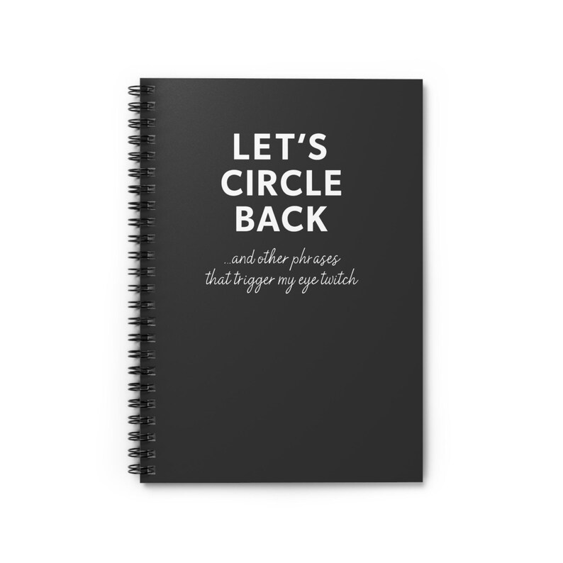 May include: A black spiral-bound notebook with the text "LET'S CIRCLE BACK" in white, along with the phrase "...and other phrases that trigger my eye twitch." The notebook has a clean, minimalist design.