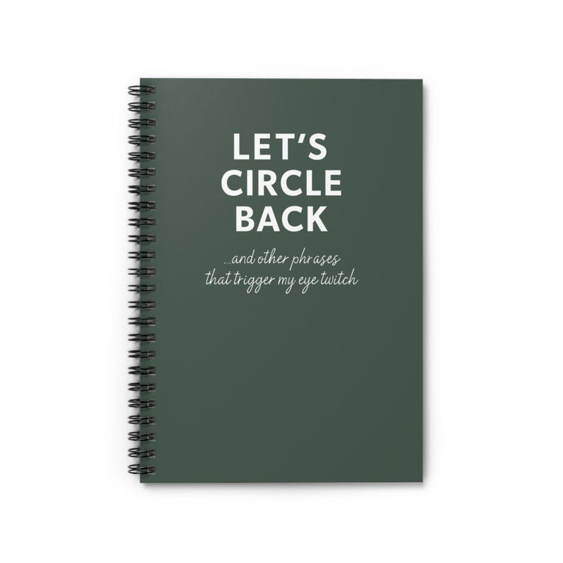 May include: A spiral-bound notebook with a dark green cover. The cover features the text "LET'S CIRCLE BACK" in large white letters, with the phrase "...and other phrases that trigger my eye twitch" below in a smaller, cursive font.