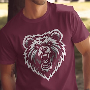 May include: A maroon t-shirt with a white graphic of a bear's head with a fierce expression.