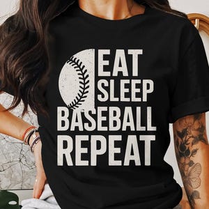 May include: Black t-shirt with a white baseball graphic and the text "Eat Sleep Baseball Repeat".