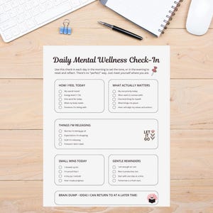 Może przedstawiać: Biała karta Daily Mental Wellness Check-In z sekcjami dotyczącymi nastroju, priorytetów i przypomnień. Karta zawiera tekst "Let it go" i znajduje się na drewnianym biurku z klawiaturą, długopisem i notatnikiem.