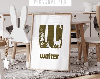 May include: A white framed print with a brown letter "W" with white forest and deer silhouettes. The name "walter" is written in white below the letter. The print is on a white rug in a room with white furniture.