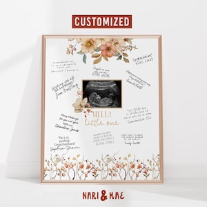 Puede incluir: Un cuadro enmarcado con un diseño floral y las palabras "Hello Little One". La impresión incluye una imagen de ultrasonido y mensajes escritos a mano. El marco es dorado, y el tema general es la decoración de la habitación del bebé.