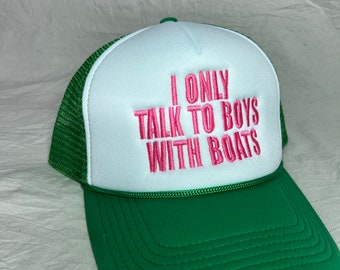 May include: Green and white trucker hat with the text "I ONLY TALK TO BOYS WITH BOATS" embroidered in pink. The hat features a green brim and mesh back, with a white front panel.