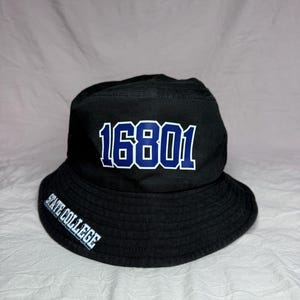 Peut inclure: Bob noir avec le numéro "16801" en lettres blanches et bleues sur le devant. Les mots "STATE COLLEGE" sont imprimés en blanc sur le côté. Le chapeau est en tissu doux.