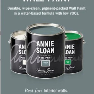 May include: Three cans of Annie Sloan Wall Paint. The cans are labeled with the brand name and the color of the paint. The colors are green, blue, and white. The text on the cans reads "Annie Sloan Wall Paint".