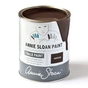 May include: A can of Annie Sloan Chalk Paint in the color Honfleur. The paint is a dark brown color and is shown with a small amount of paint dripping down the side of the can. The can has a white label with the Annie Sloan logo and the text "Chalk Paint" and "Honfleur".