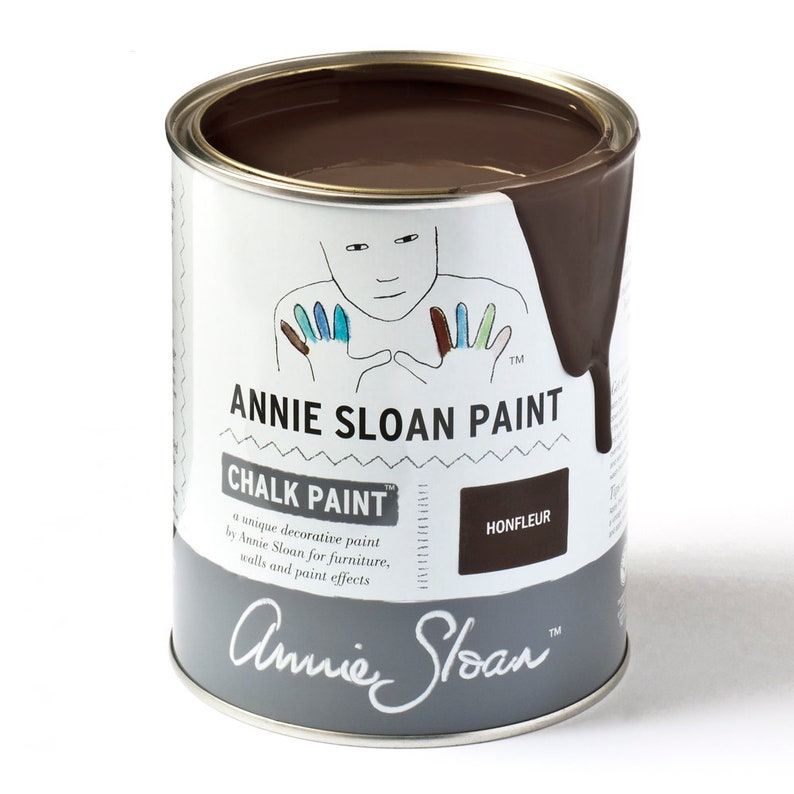 May include: A can of Annie Sloan Chalk Paint in the color Honfleur. The paint is a dark brown color and is shown with a small amount of paint dripping down the side of the can. The can has a white label with the Annie Sloan logo and the text "Chalk Paint" and "Honfleur".