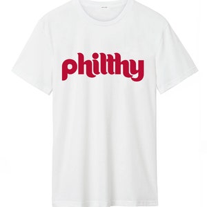 May include: White t-shirt with a red "philthy" graphic printed on the front.