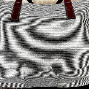 以下が含まれることがあります： 黒と白のストライプのトートバッグで、茶色の革のハンドルが付いています。