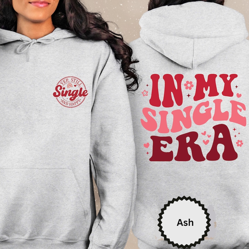 May include: Gray hoodie with a red and pink graphic that says "Yep, Still Single and Happy" on the front and "In My Single Era" on the back. The hoodie has a drawstring hood and a kangaroo pocket.