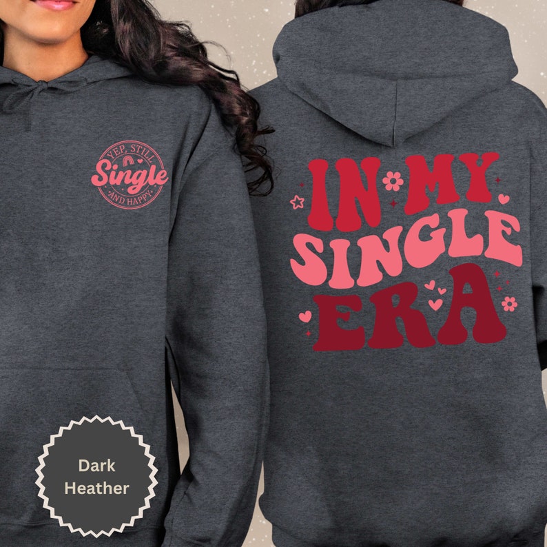 May include: Dark heather grey hoodie with the text "Yep, Still Single and Happy" in a pink circle on the front and "In My Single Era" in pink and red letters on the back.