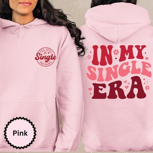 May include: Pink hoodie with the text "Yep, Still Single and Happy" on the front and "In My Single Era" on the back. The text is in a retro font with hearts and stars.