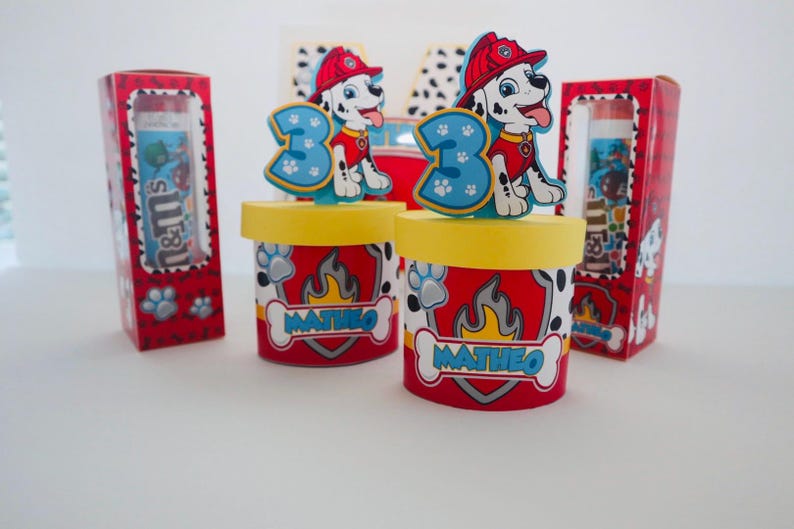 Puede incluir: Contenedores de fiesta rojos y amarillos con un personaje de Patrulla Canina como adorno. Los contenedores est&aacute;n decorados con un patr&oacute;n de huellas de patas y el nombre "Matheo".