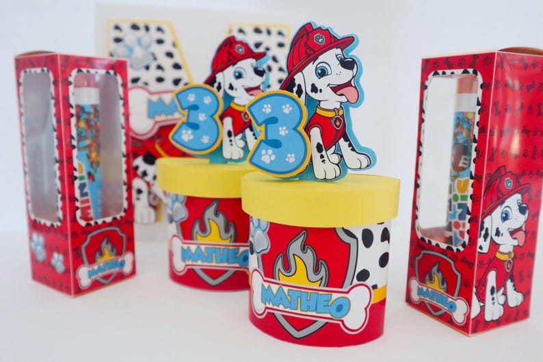 Puede incluir: Cajas de regalo de fiesta rojas y amarillas con una ventana transparente. Las cajas presentan un perro d&aacute;lmata de dibujos animados con un sombrero de bombero y el nombre "Matheo".