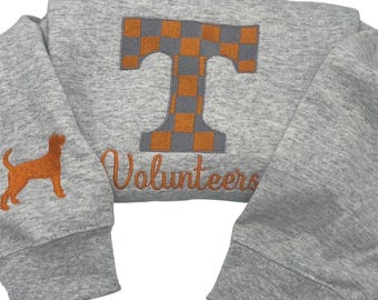 May include: A gray sweatshirt with an orange and gray checkered "T" and the word "Volunteers" embroidered on the front. A small orange dog is embroidered on the left sleeve.