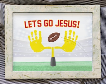 May include: A framed artwork with a football theme. The artwork features the text "LET'S GO JESUS!" in red letters. Yellow handprints form the goalposts, with a brown football in the center. The background depicts a football field and stadium.
