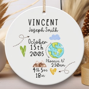 May include: White ceramic ornament with a world map, mountains, and a heart. It says "VINCENT Joseph Smith October 15th 2005 Phoenix, AZ 2:50am 4lb 5oz 18in"
