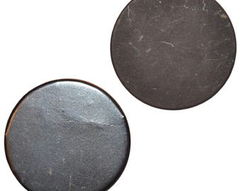 May include: Two dark gray, circular objects are displayed against a white background. The objects have a slightly textured surface with subtle variations in color. The overall appearance suggests a vintage or antique aesthetic.