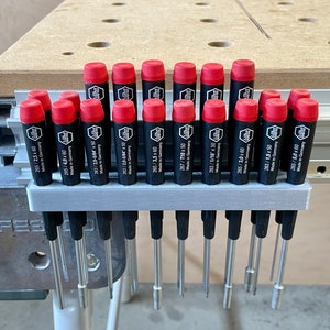 May include: A gray plastic holder with 18 red and black screwdrivers. The screwdrivers are labeled with their size and "Made in Germany".