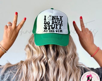 Può includere: Un cappellino da camionista verde e bianco con la scritta "I ONLY DO BUTT STUFF AT THE GYM". Il cappello ha una visiera e un retro in rete verdi, con un pannello frontale bianco. Il testo è nero, con una grafica di pesca.