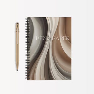 May include: A spiral bound notebook with a brown and white abstract design. The cover features the text "PEN & PAPER".
