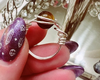May include: A silver wire wrapped ring with a brown tiger's eye stone.