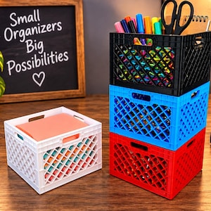 May include: A set of four small plastic storage crates in black, blue, red, and white with a diamond-patterned lattice design. The black crate holds colorful markers and scissors. A chalkboard sign displays the text Small Organizers Big Possibilities.