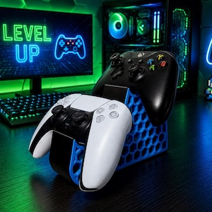 May include: A blue 3D-printed honeycomb-patterned controller stand holding a white and black game controller in the front and a black game controller in the back. The stand features a geometric hexagonal structure designed to support two gaming controllers.