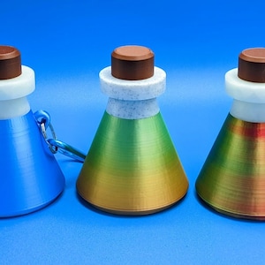 May include: Three small, cone-shaped bottles with brown lids and a silver key chain. The bottles are blue, green and gold, and red.