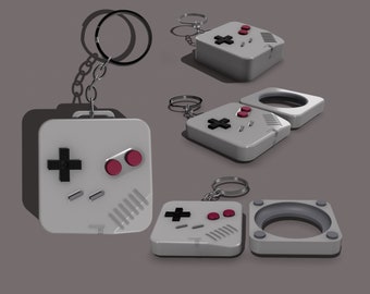 May include: A white and gray keychain shaped like a retro video game controller with red buttons. The keychain is attached to a silver ring.