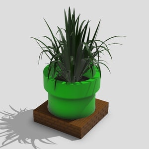 Puede incluir: Un macetero verde en forma de tubo con una base de ladrillo marrón, que contiene una planta verde con hojas largas y delgadas.