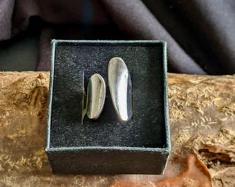May include: Two silver rings in a black velvet box. The rings are both oval shaped and have a smooth, polished finish.
