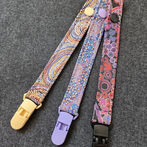 May include: Three patterned dummy clips with different designs. One clip has a cream clasp and button, another has a lilac clasp and button, and the third has a black clasp and button. The patterns include dots and paisley-like designs in various colours.