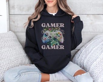 May include: Black hoodie with a floral design featuring a video game controller and the text "Gamer" on the front.