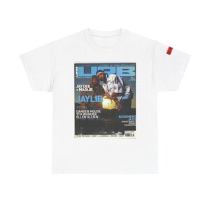 May include: A white t-shirt with a printed image of a magazine cover featuring Jay Dee and Madlib. The magazine cover is titled "URB" and features the text "Jaylib" in large, bold letters. The magazine cover also includes the text "Danger Mouse", "9th Wonder", and "Ellen Allien".