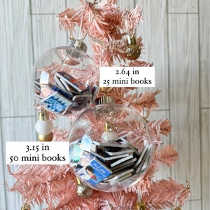 May include: Two clear glass ornaments filled with miniature books. The larger ornament is 3.15 inches in diameter and holds 50 mini books. The smaller ornament is 2.64 inches in diameter and holds 25 mini books. Both ornaments are hanging on a pink artificial Christmas tree.