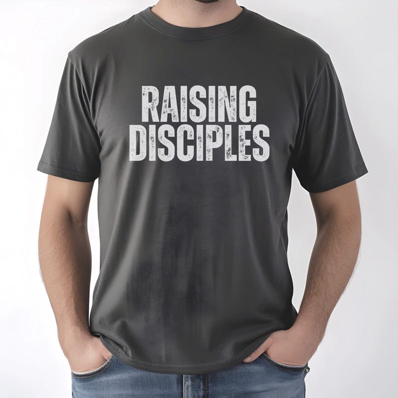 May include: A dark gray t-shirt with the text "RAISING DISCIPLES" printed in white on the front.