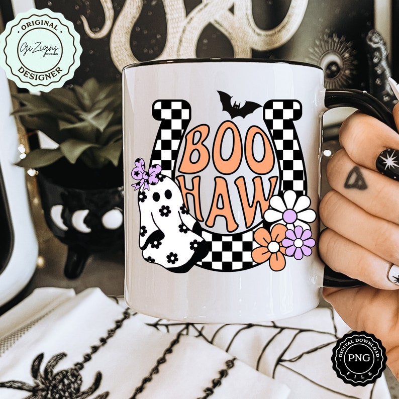 May include: White ceramic mug with a black rim and handle, featuring a Halloween-themed design. The design includes the words "BOO HAW" in orange, a ghost, flowers, and a bat. The mug also has a horseshoe and a checkered pattern.
