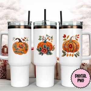 Peut inclure: Trois gobelets en acier inoxydable blanc avec couvercles et pailles. Chaque gobelet pr&eacute;sente un motif brod&eacute; de citrouille avec des accents floraux. Les citrouilles sont orange avec des tiges brunes et des feuilles vertes. Les accents floraux sont dans des tons de rouge, orange, jaune, vert et bleu.