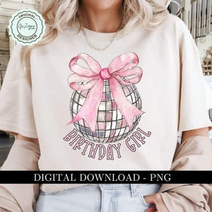 Op de afbeelding: Een wit T-shirt met een roze glitterbal en een roze strik erboven. De tekst "Birthday Girl" staat onder de bal.