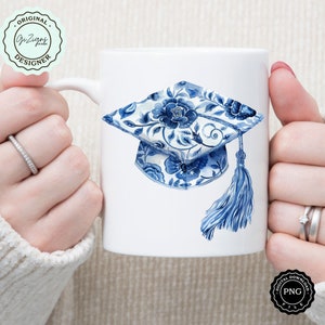 May include: White ceramic mug with a blue and white floral graduation cap design. The cap has a tassel and is decorated with a blue and white floral pattern.