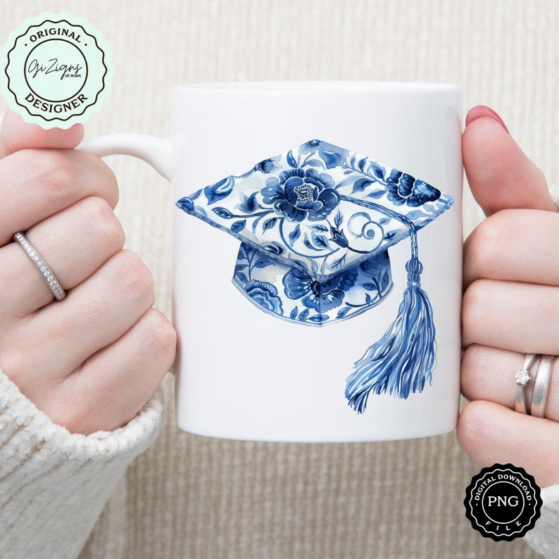 May include: White ceramic mug with a blue and white floral graduation cap design. The cap has a tassel and is decorated with a blue and white floral pattern.