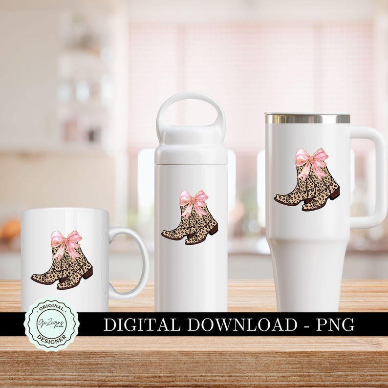 K&ouml;nnte beinhalten: Drei wei&szlig;e Tassen mit einem Design aus rosa Schleifen und Leopardenmuster-Cowboots. Die Tassen sind in Standardgr&ouml;&szlig;e, als Reisebecher und als kleinere Tasse. Der Text "Original Designs" befindet sich auf der kleineren Tasse.